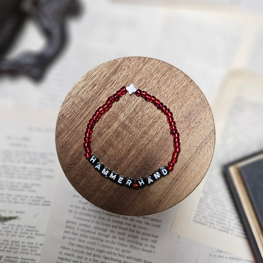 Bracelet with red and black beads on a wooden stand over a book