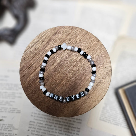 Black and white beaded bracelet on a wooden coaster with a book in the background