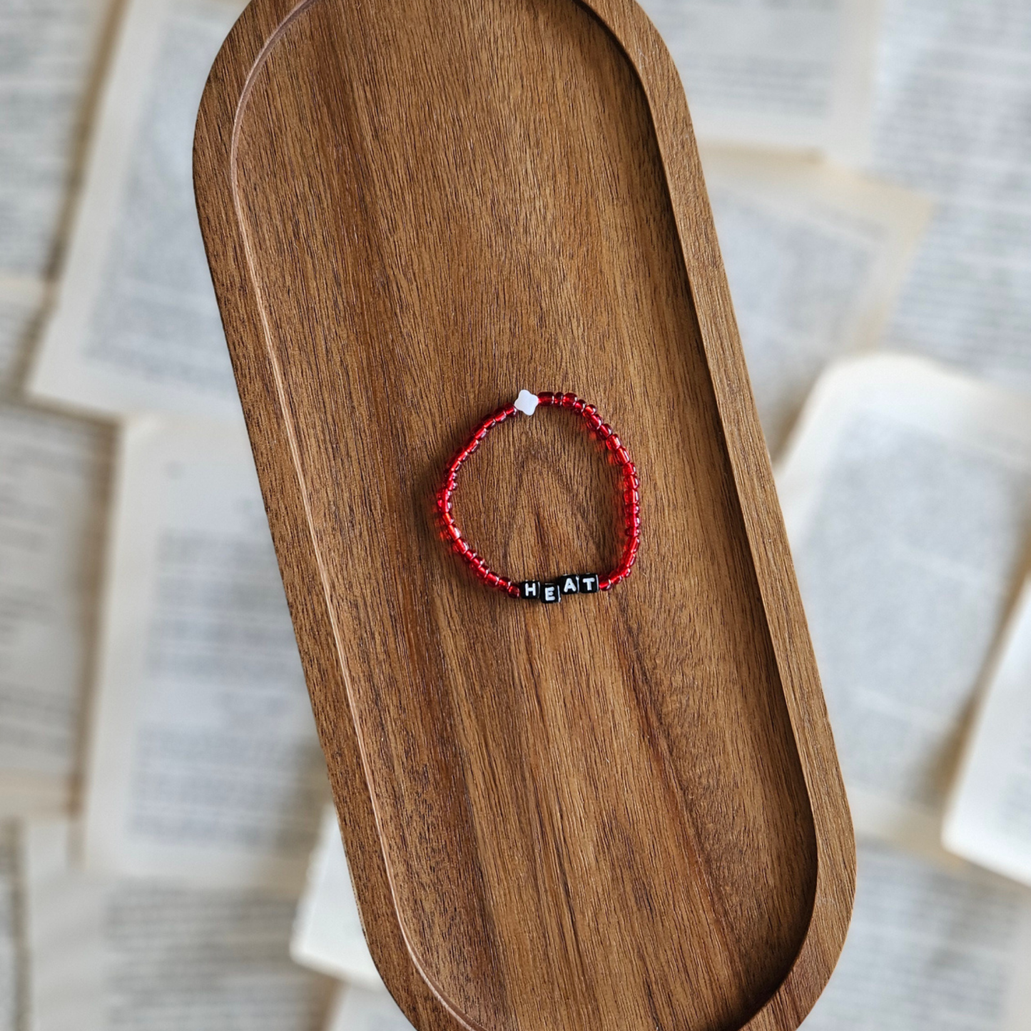Red bracelet with black beads on a wooden tray