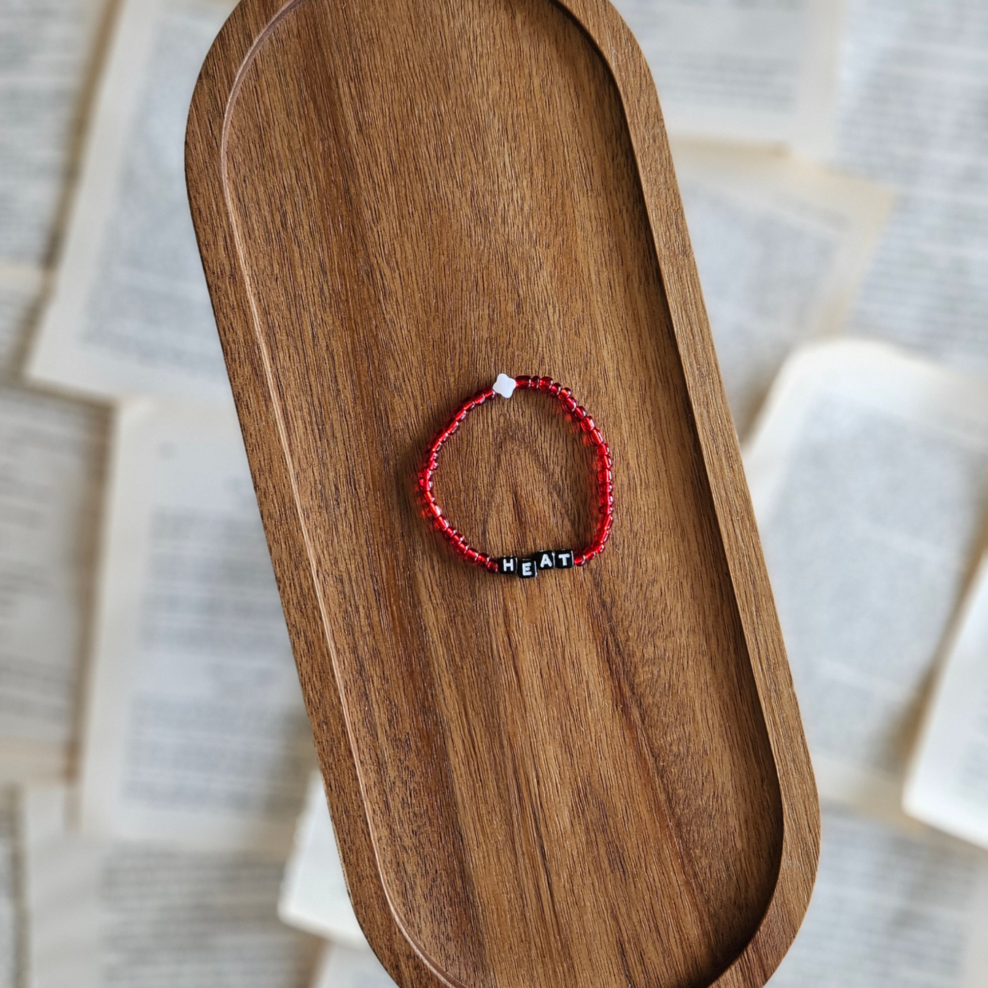 Red bracelet with black beads on a wooden tray