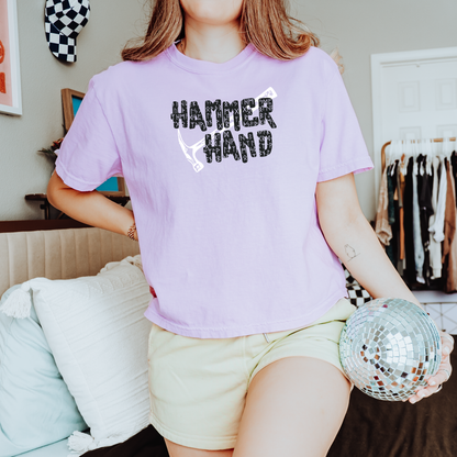 Person wearing a pink t-shirt with 'HAMMER HAND' text, holding a disco ball in a casual setting.