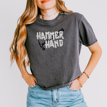 Person wearing a dark gray t-shirt with 'HAMMER HAND' text and graphic on a plain background
