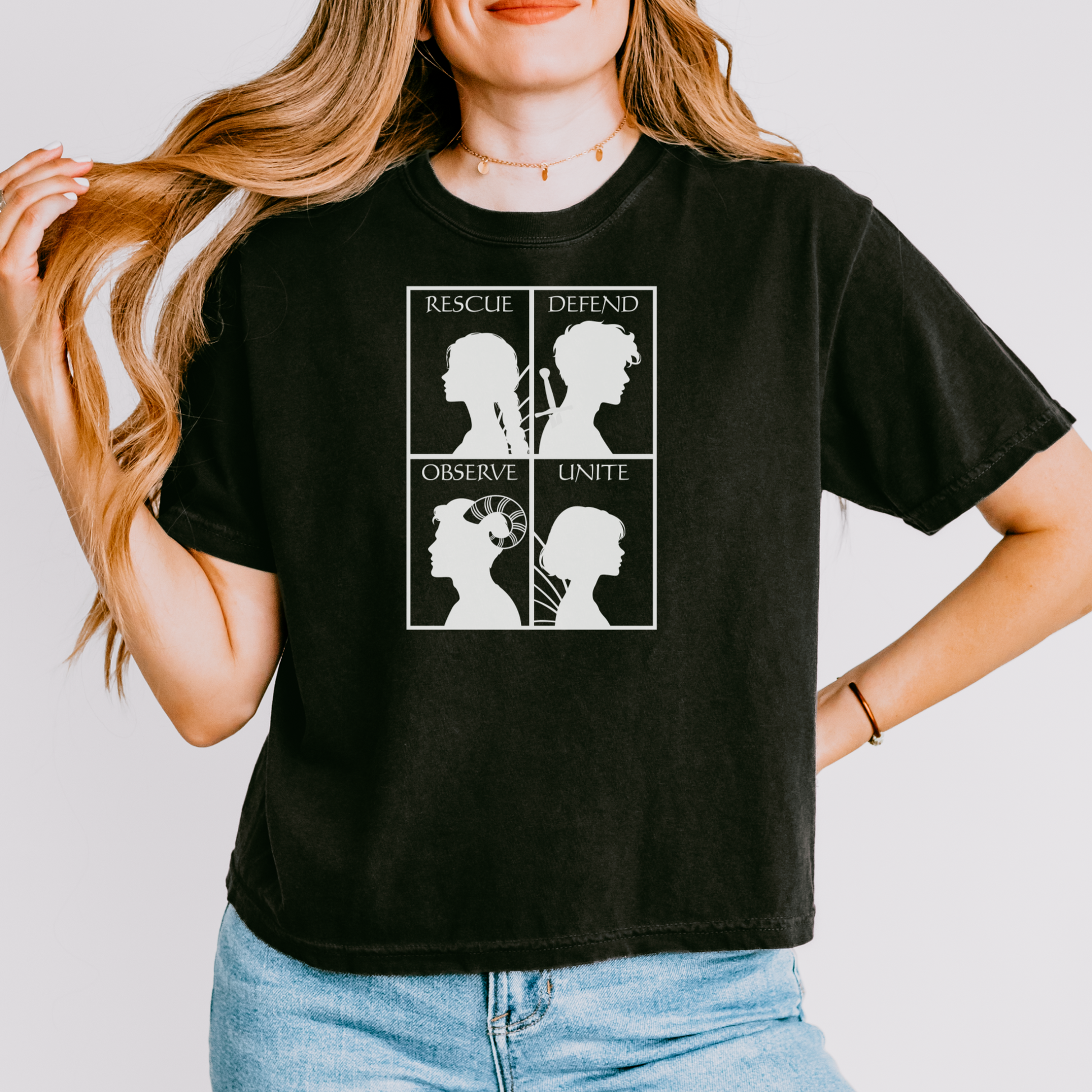 A woman wearing a black graphic t-shirt with a white four-panel design featuring silhouettes and the words 'Rescue', 'Defend', 'Observe', and 'Unite'.