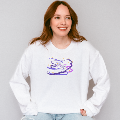 A woman with red hair wearing a white crewneck sweatshirt with a purple and blue abstract graphic on the chest, paired with light blue jeans, against a plain light gray background.