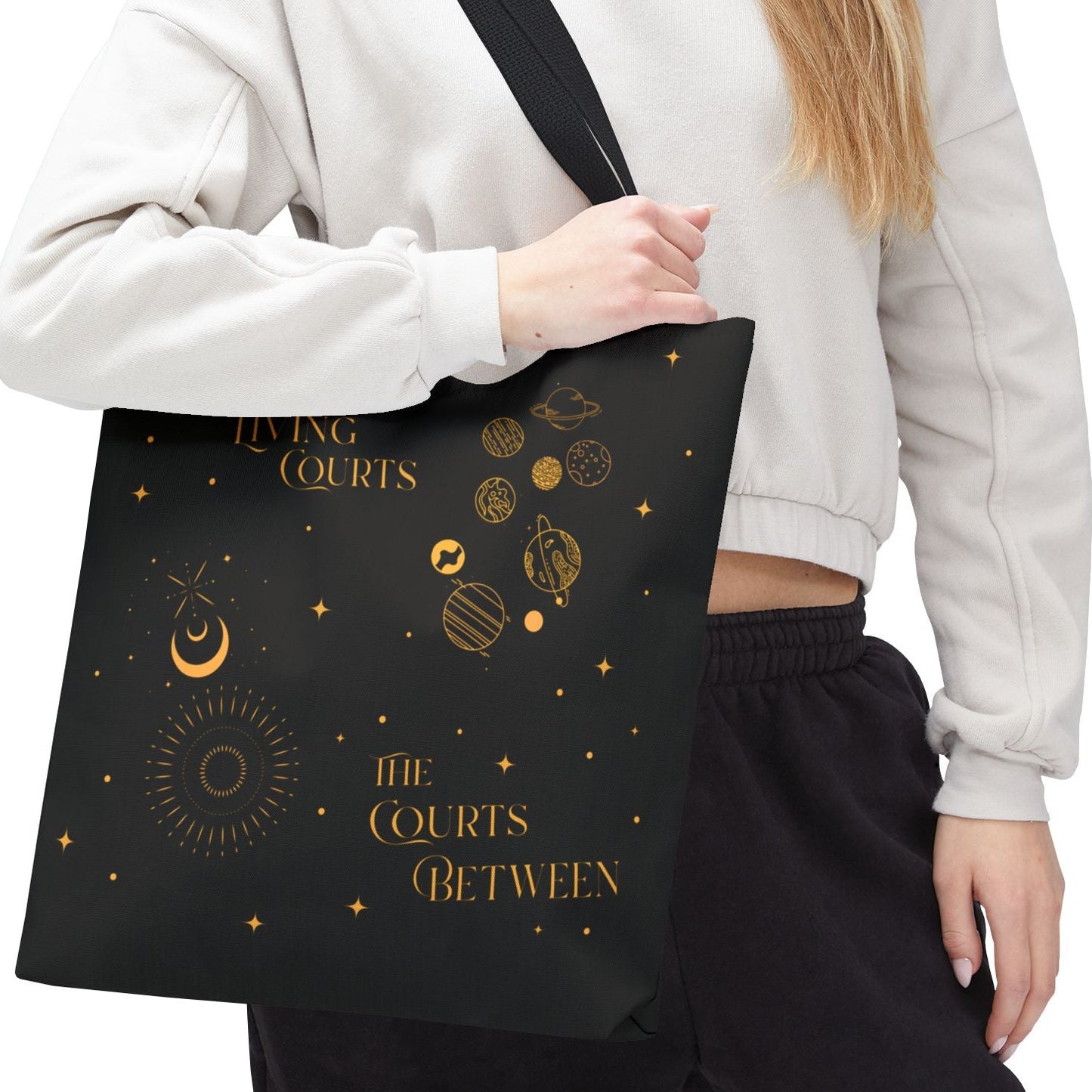 Person holding a black tote bag with planetary courts on a white background.