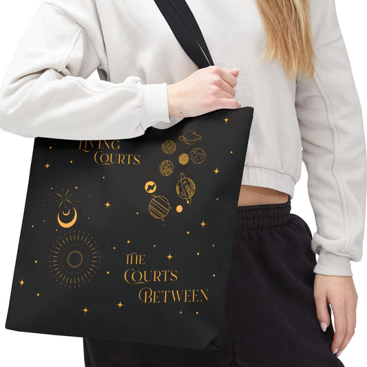 Person holding a black tote bag with planetary courts on a white background.